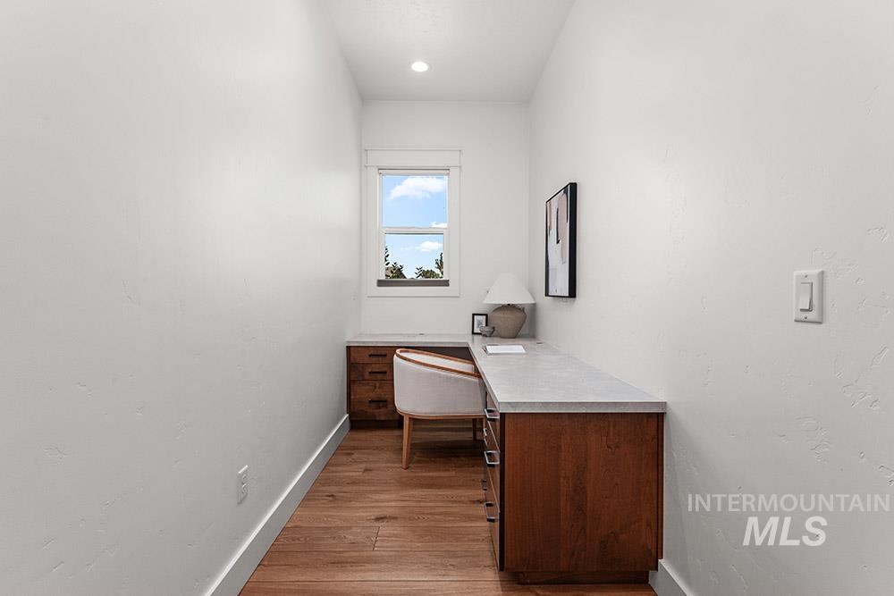 Office area featuring light wood-style floors and built in study area