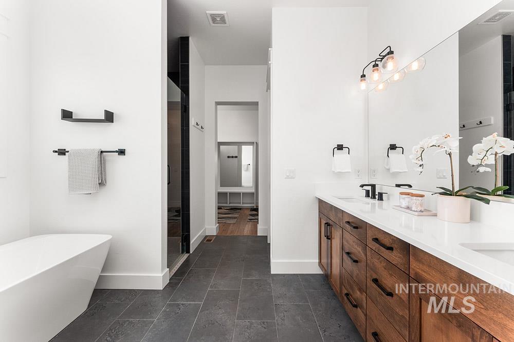 Full bath featuring double vanity, a freestanding tub, and a shower stall