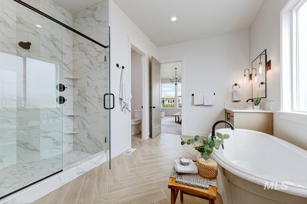 Full bathroom featuring vanity, parquet floors, a marble finish shower, a freestanding bath, and recessed lighting
