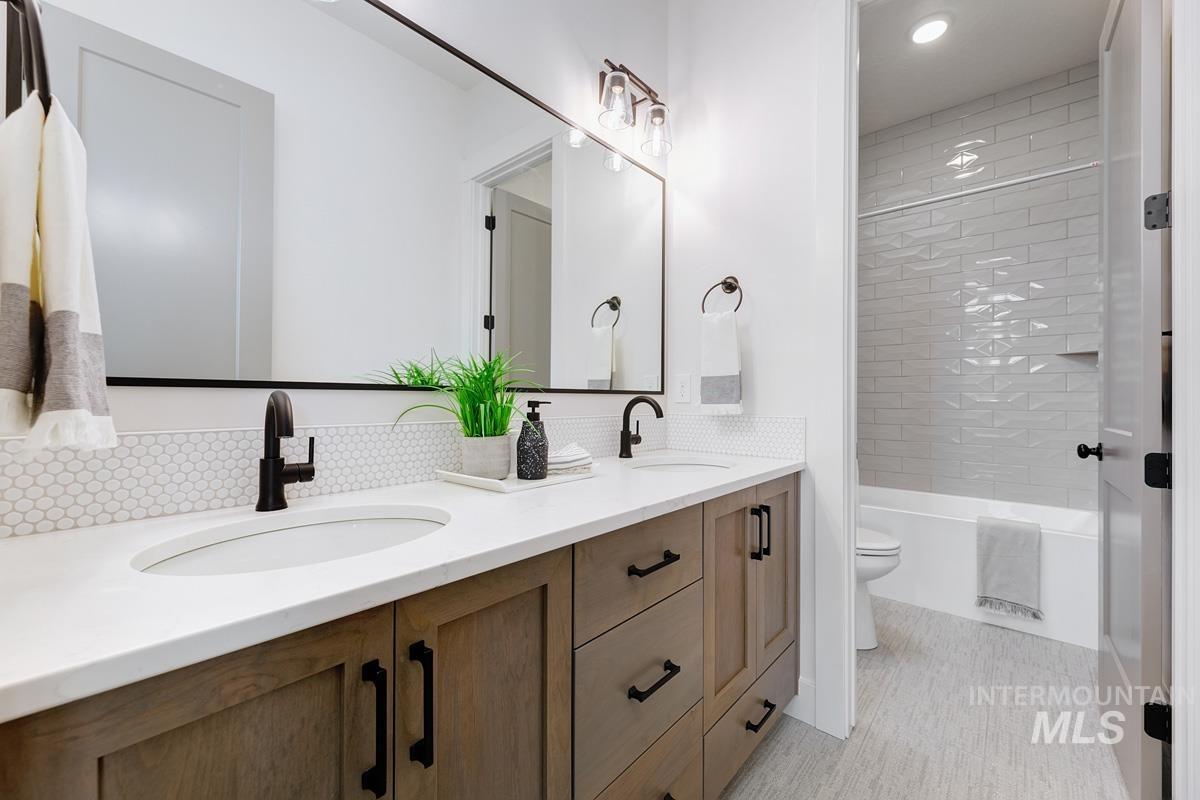 Full bath featuring double vanity, shower / bathtub combination, and recessed lighting