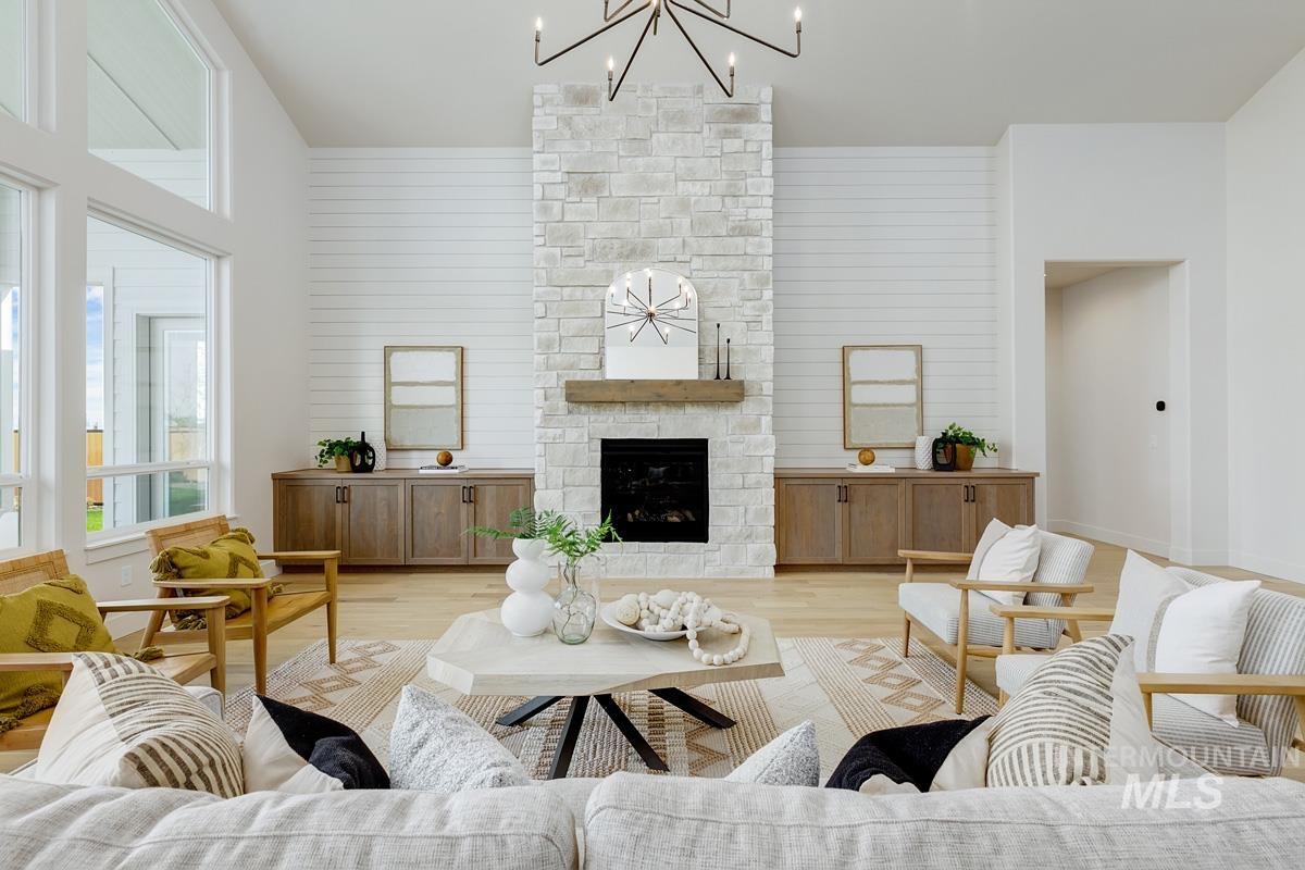 Living room with wood finished floors, a fireplace, a chandelier, wooden walls, and a towering ceiling