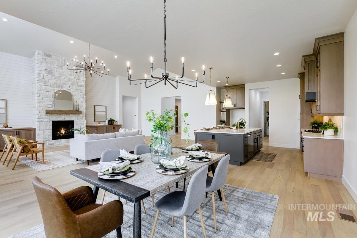 Dining room with a chandelier, light wood-style floors, a fireplace, and recessed lighting