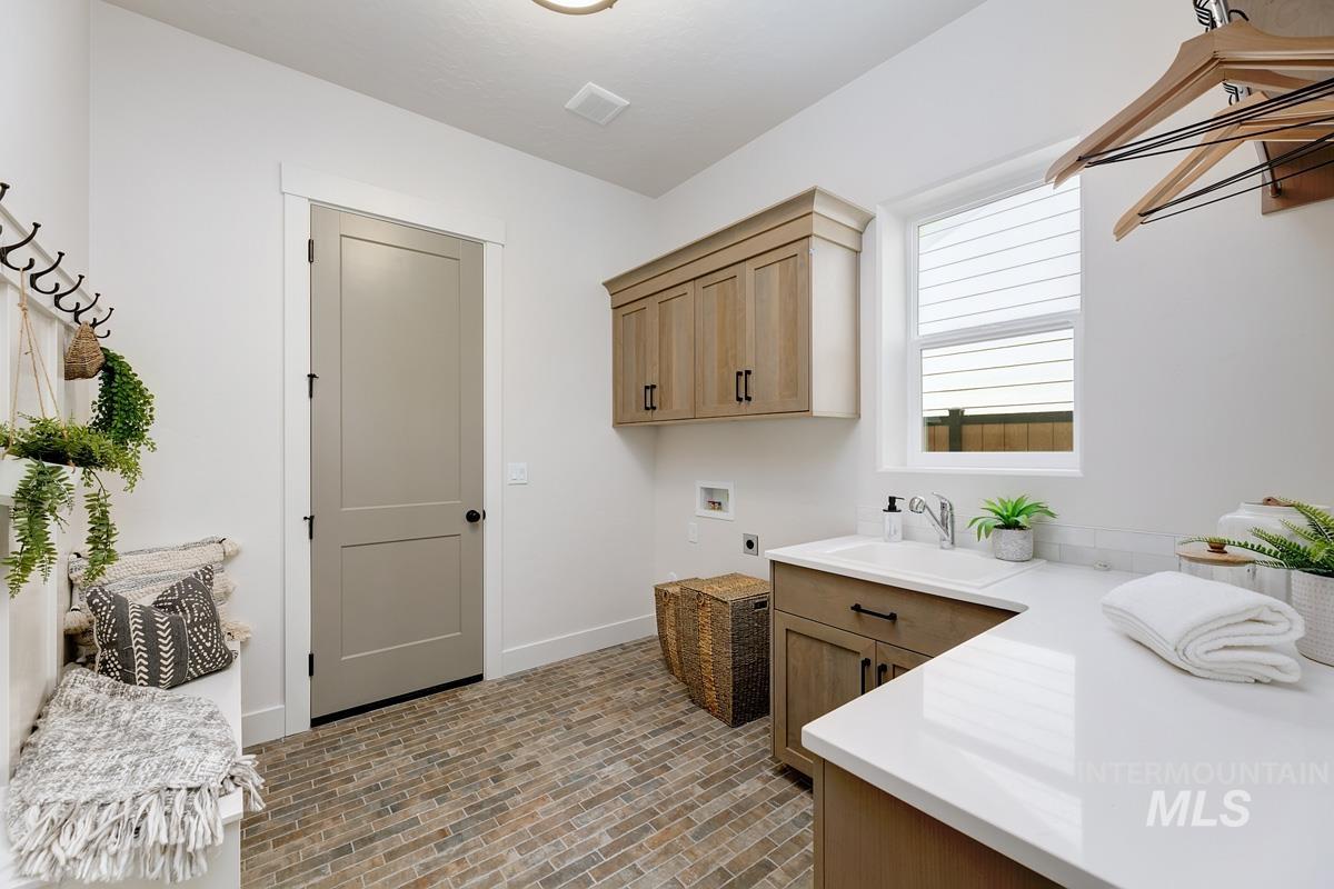 Washroom with brick patterned floors, cabinet space, washer hookup, and hookup for an electric dryer