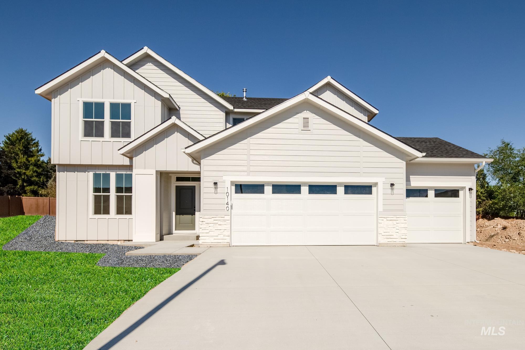 Modern farmhouse with an attached garage, concrete driveway, stone siding, and board and batten siding