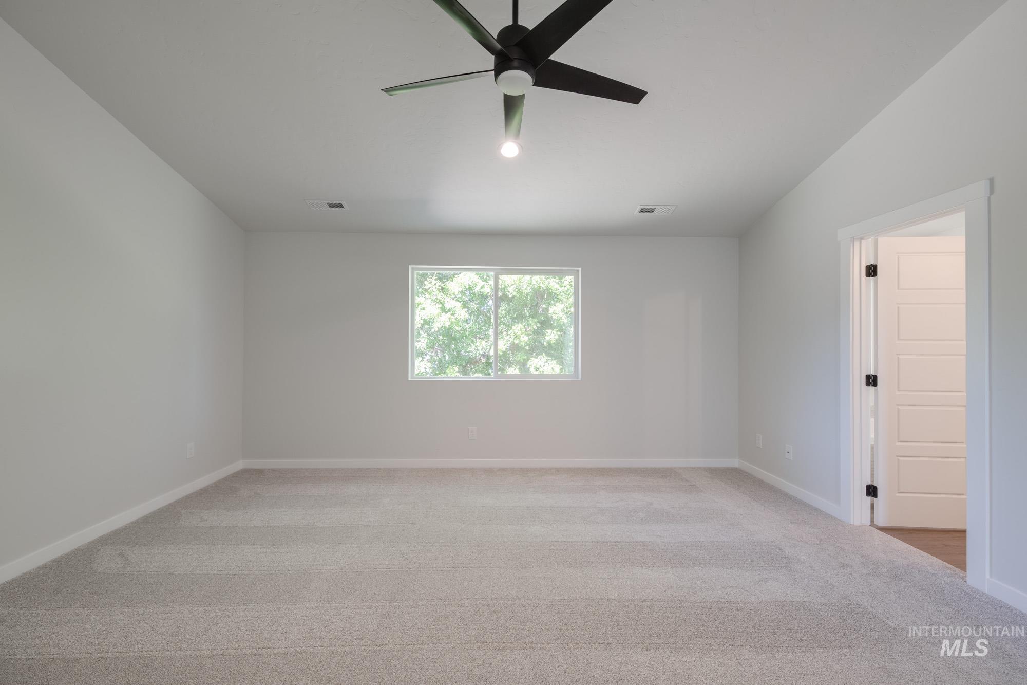 Spare room featuring light carpet and ceiling fan