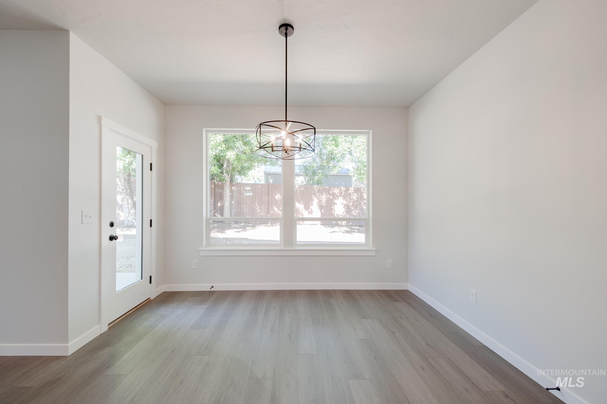 Unfurnished dining area featuring wood finished floors and a chandelier