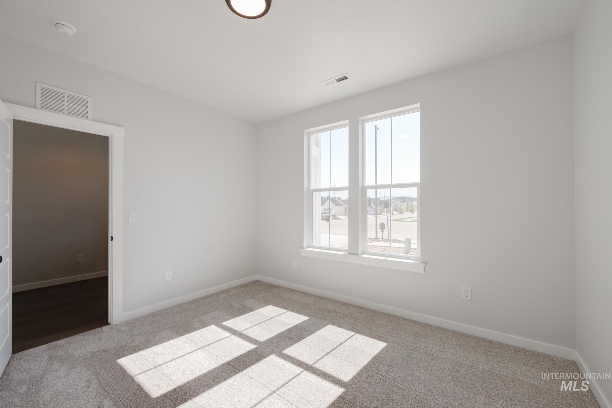 Spare room featuring light carpet and baseboards