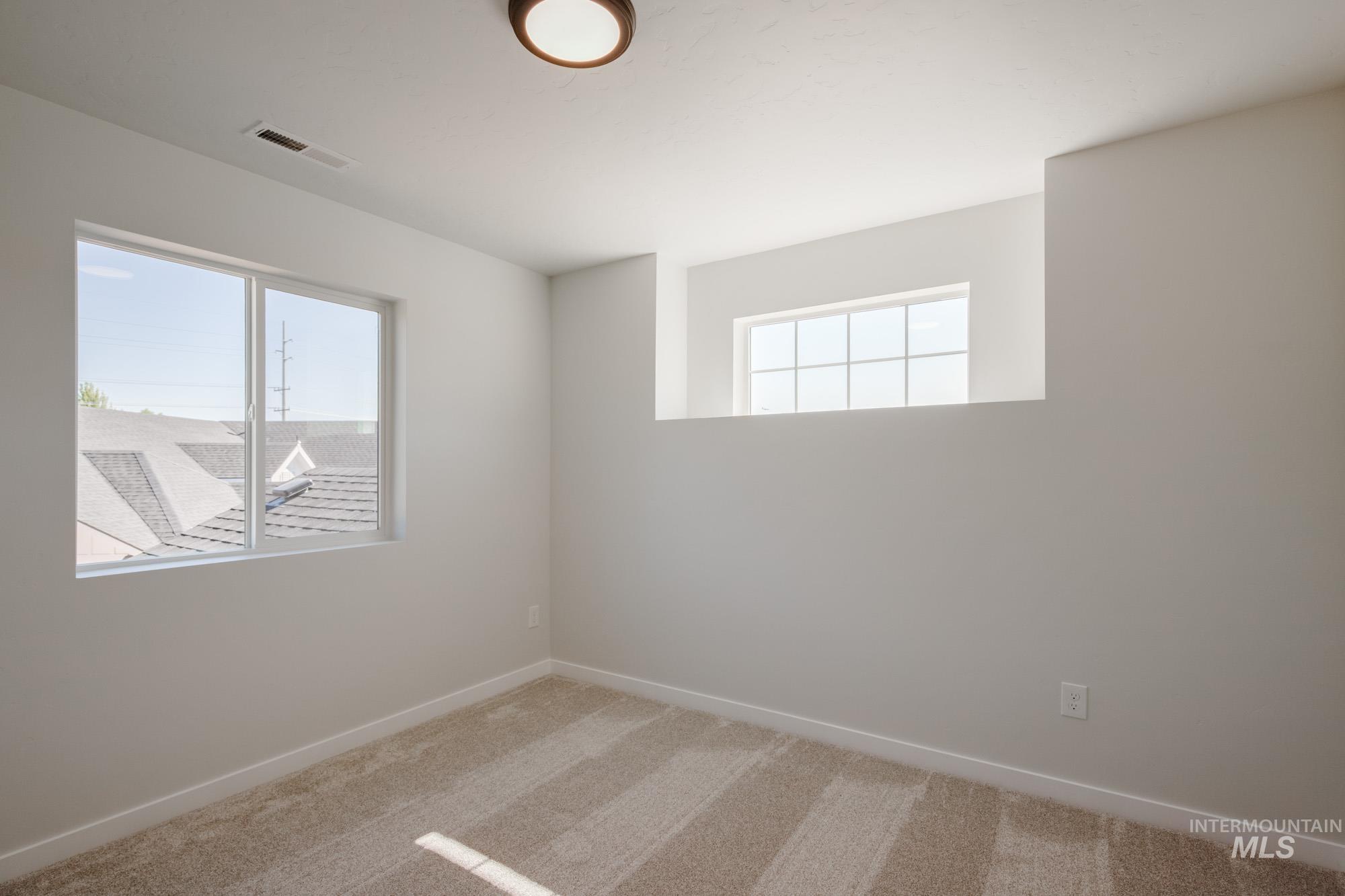 Empty room with light colored carpet and baseboards