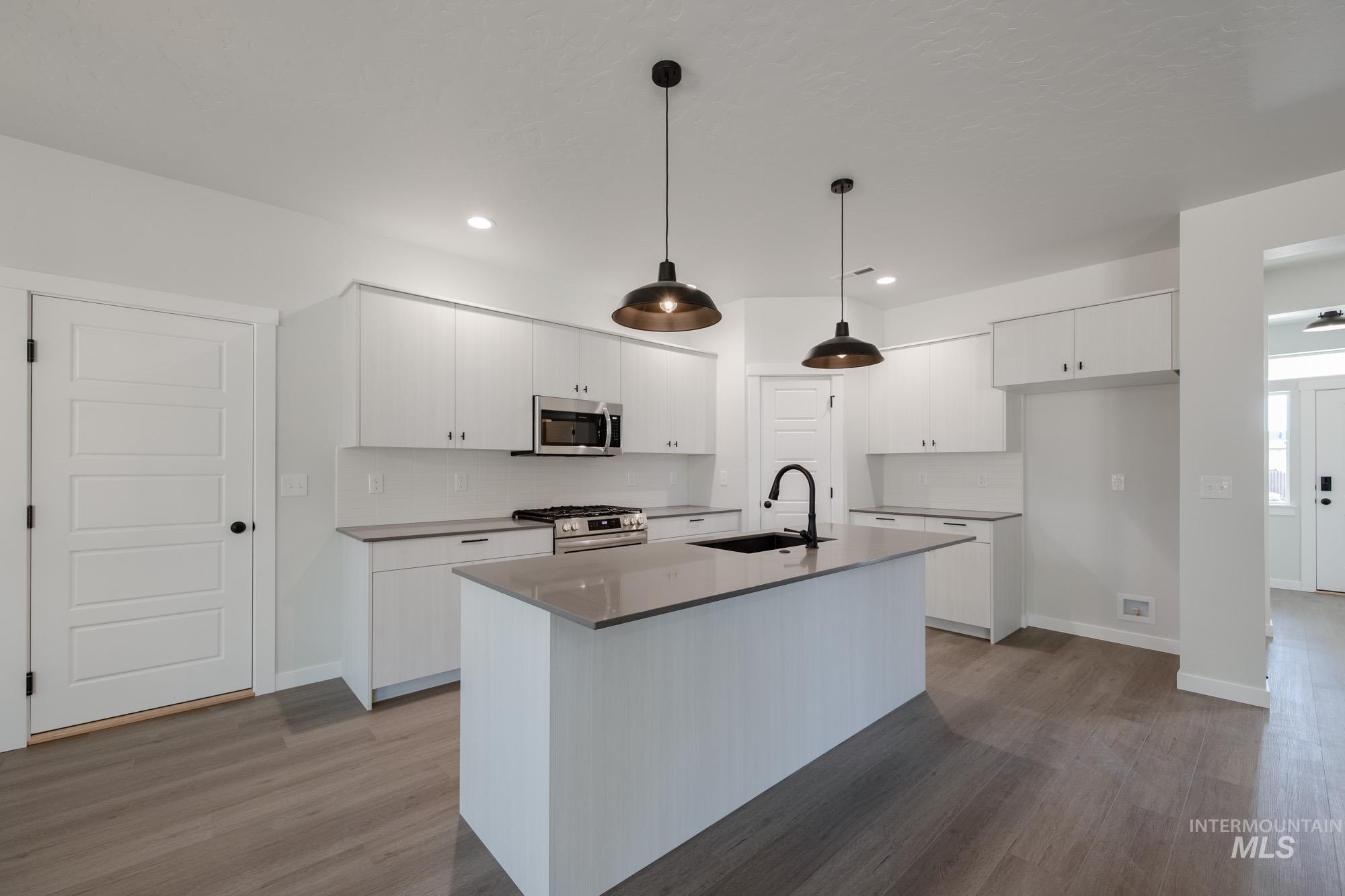 Kitchen featuring stainless steel appliances, dark wood-style flooring, backsplash, and recessed lighting