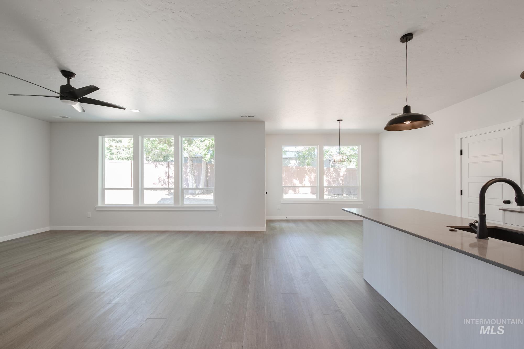 Kitchen featuring wood finished floors, decorative light fixtures, a ceiling fan, and open floor plan