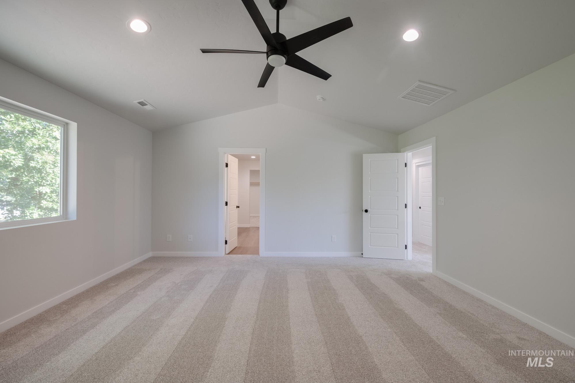 Unfurnished bedroom featuring lofted ceiling, recessed lighting, light colored carpet, connected bathroom, and a ceiling fan