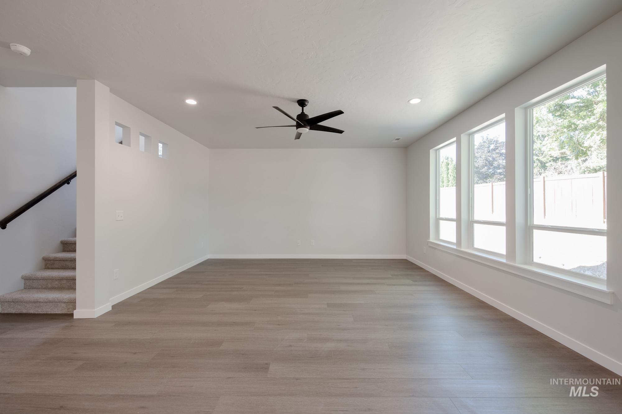 Empty room featuring recessed lighting, a smoke detector, light wood-type flooring, stairway, and ceiling fan