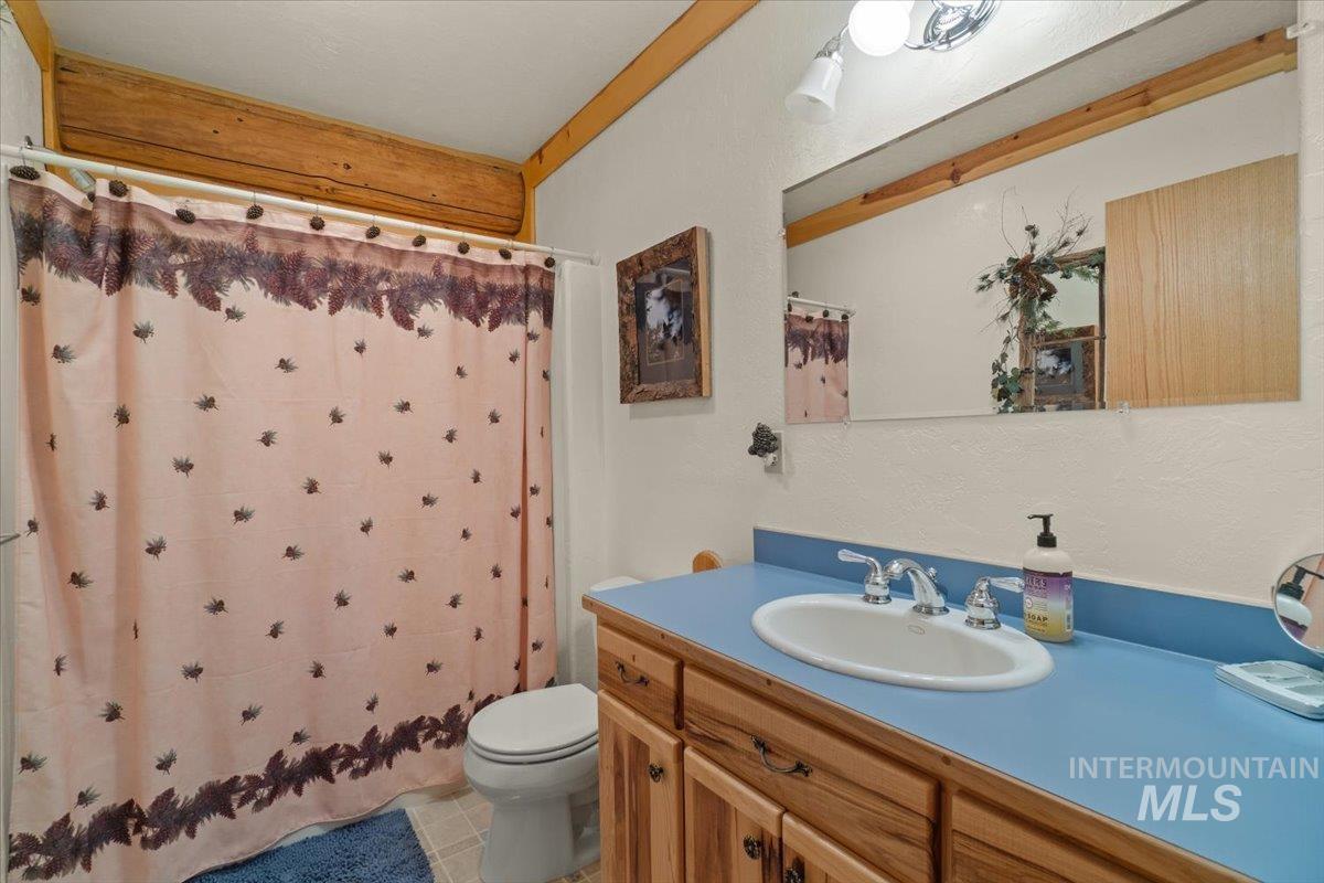 Full bath featuring vanity, curtained shower, and light tile patterned flooring
