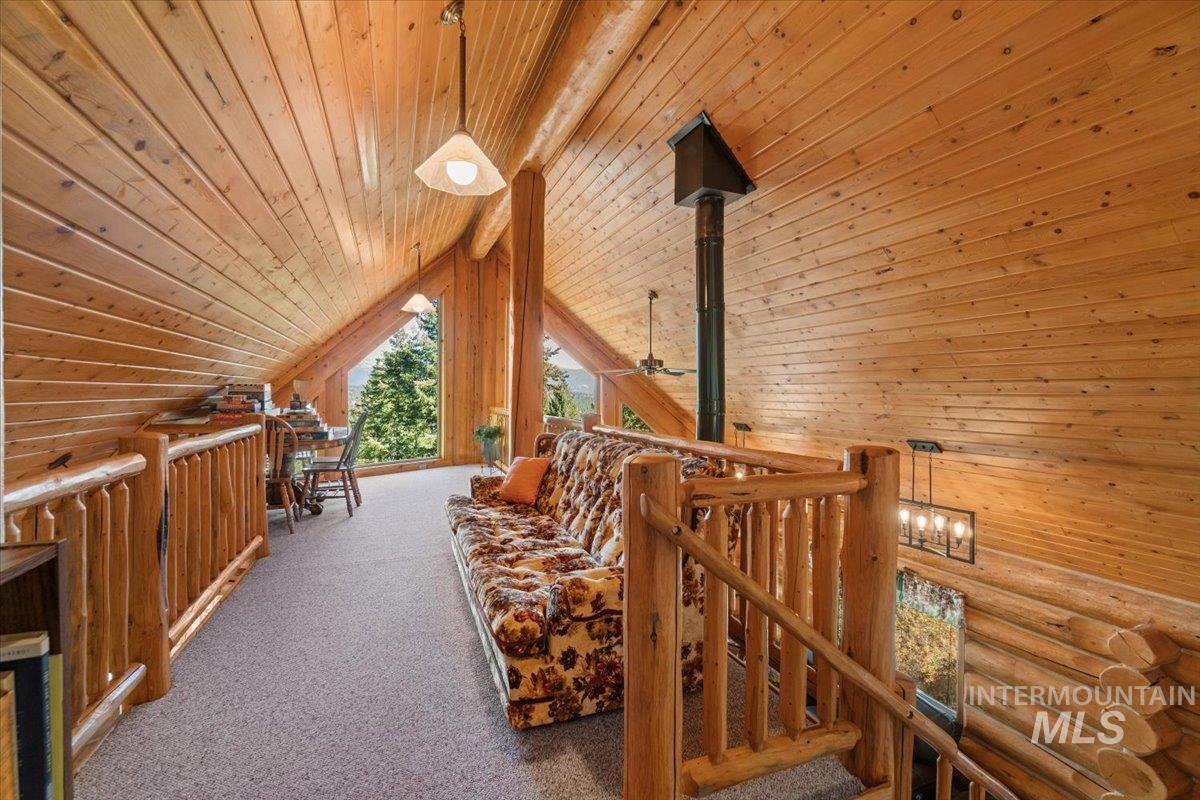 Corridor featuring wood ceiling, an upstairs landing, wooden walls, and carpet flooring
