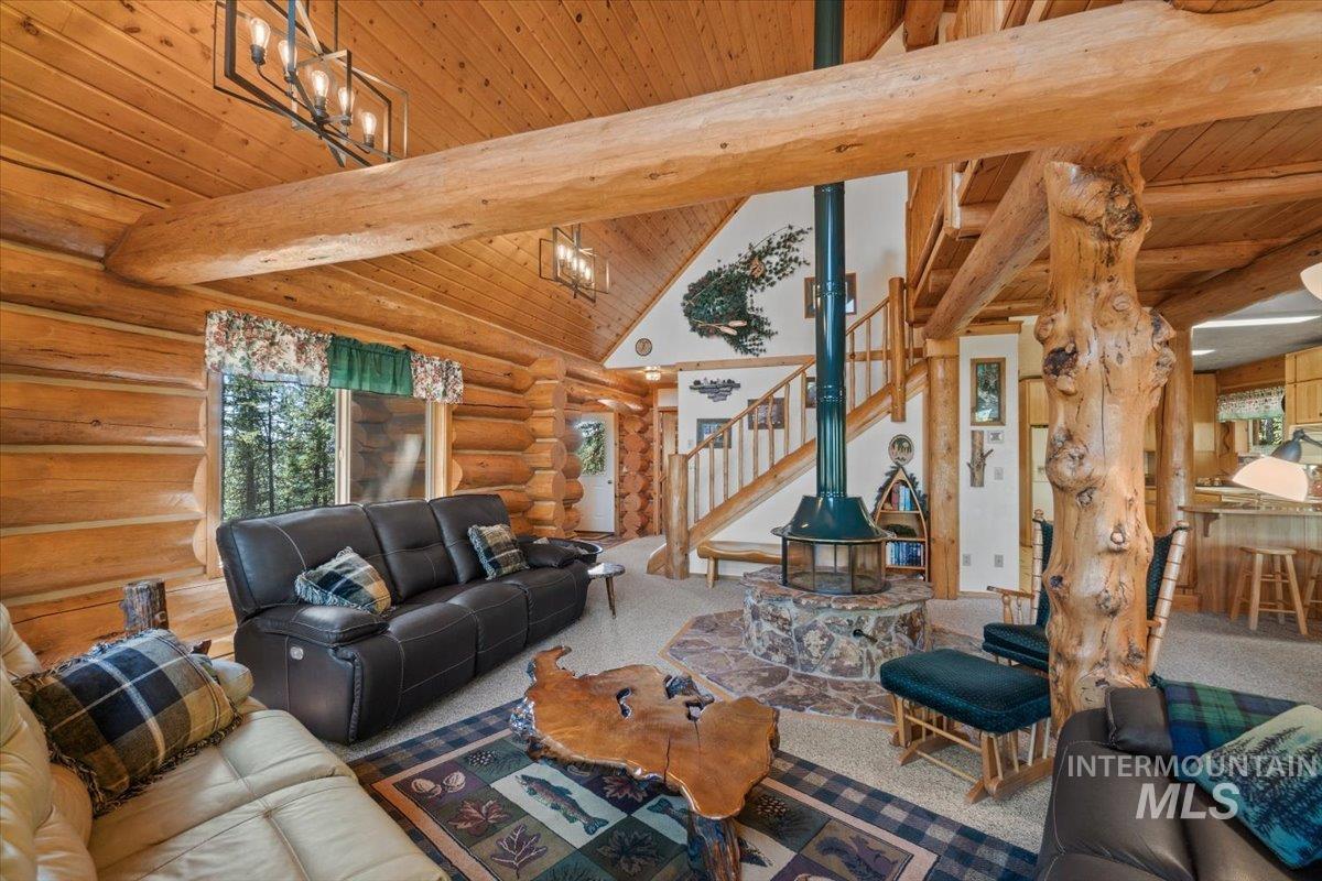 Living room featuring a wooden ceiling with exposed beams, stairs, rustic walls, high vaulted ceiling, and carpet