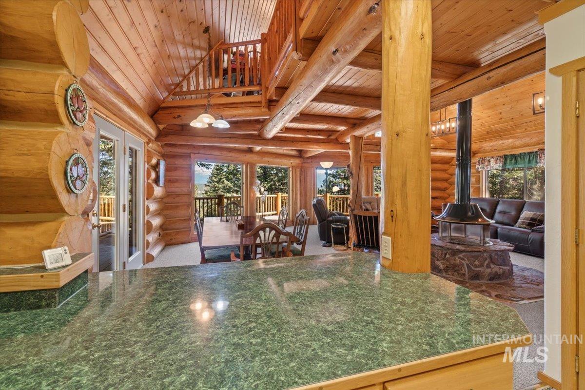 Kitchen featuring rustic walls, a wood stove, a wood ceiling with exposed beams, dark countertops, and french doors