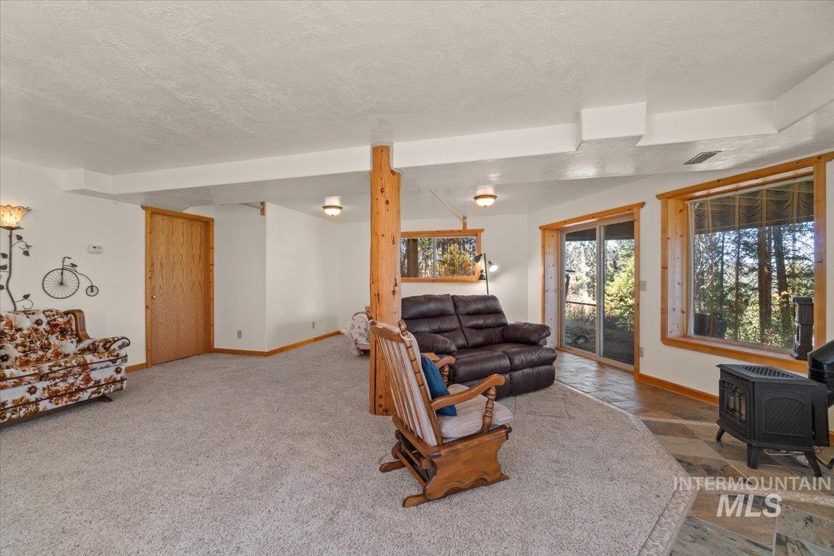 Living room with a wood stove, a textured ceiling, and stone tile flooring