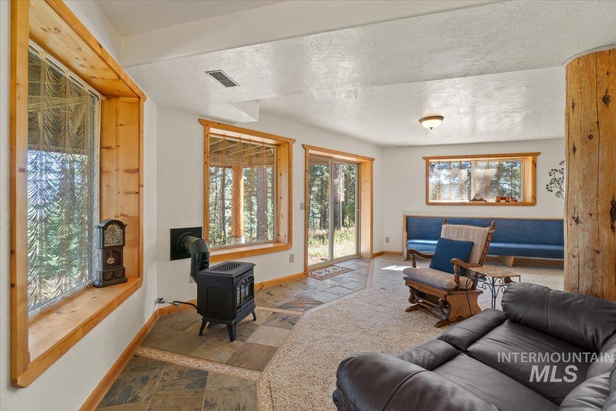 Living room with a wood stove, stone finish floors, and a textured ceiling