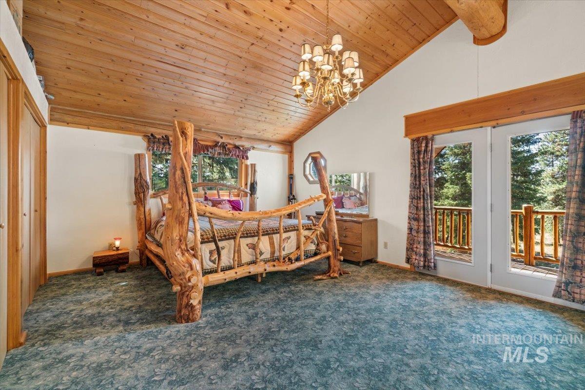 Carpeted bedroom with access to outside, a chandelier, wood ceiling, and high vaulted ceiling