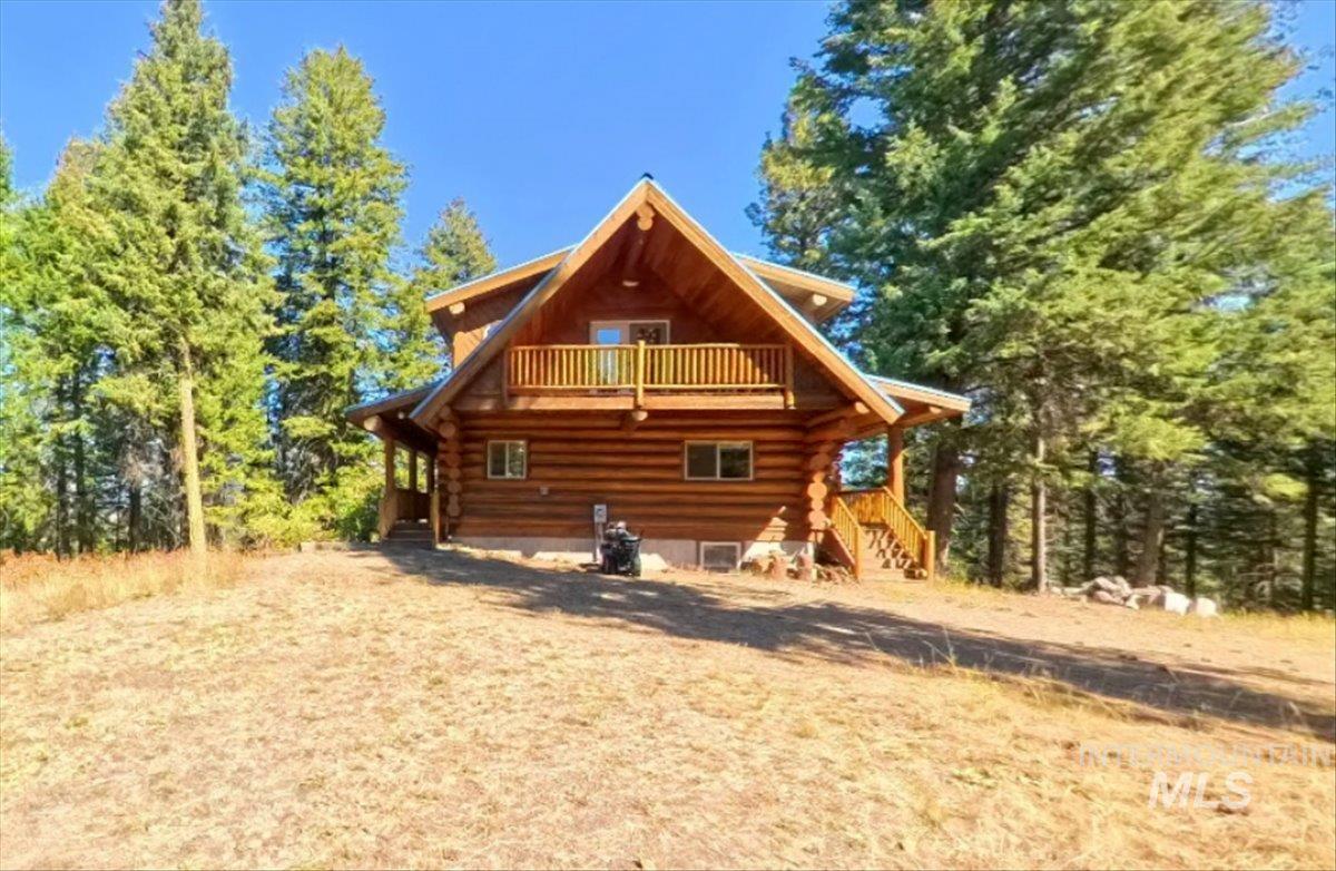Back of property with stairs, a balcony, and log siding