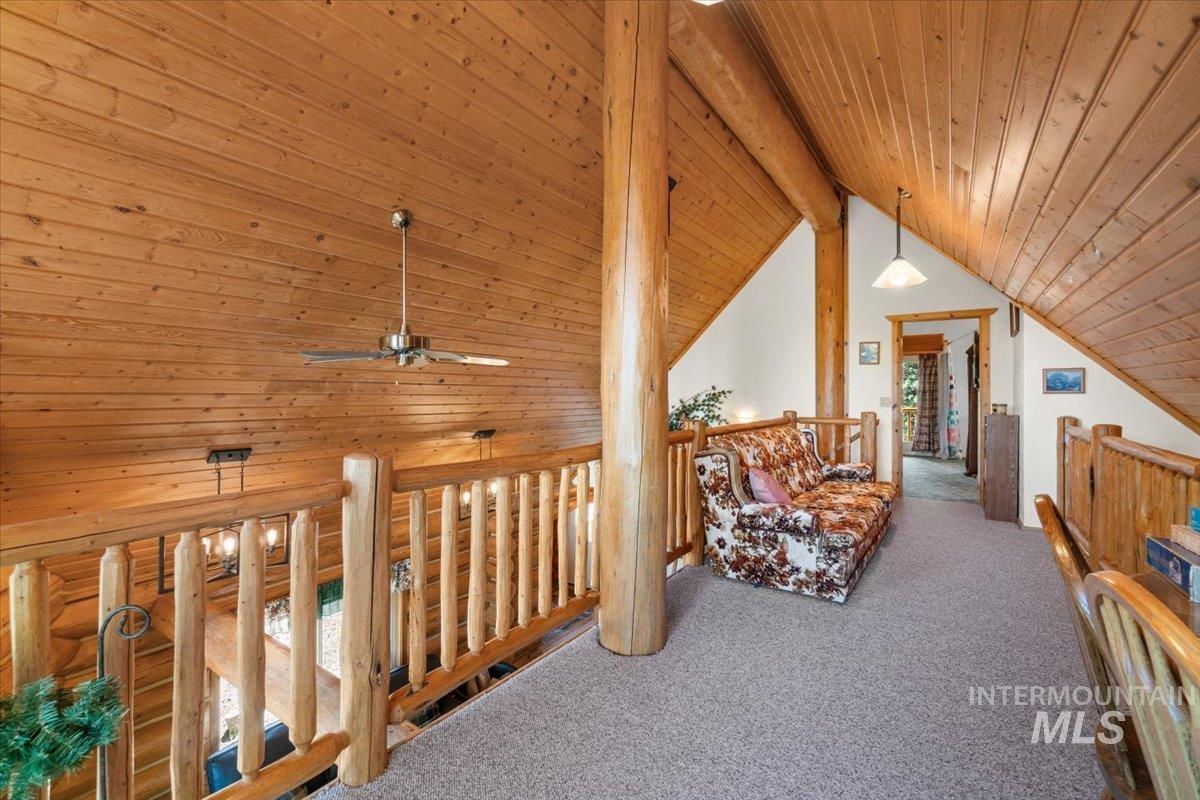 Sitting room featuring wooden ceiling, carpet, and an upstairs landing