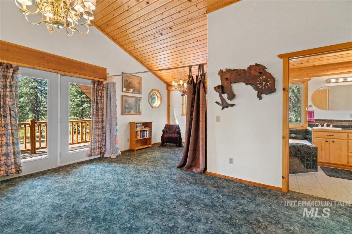Unfurnished room featuring a chandelier, carpet floors, wood ceiling, and high vaulted ceiling