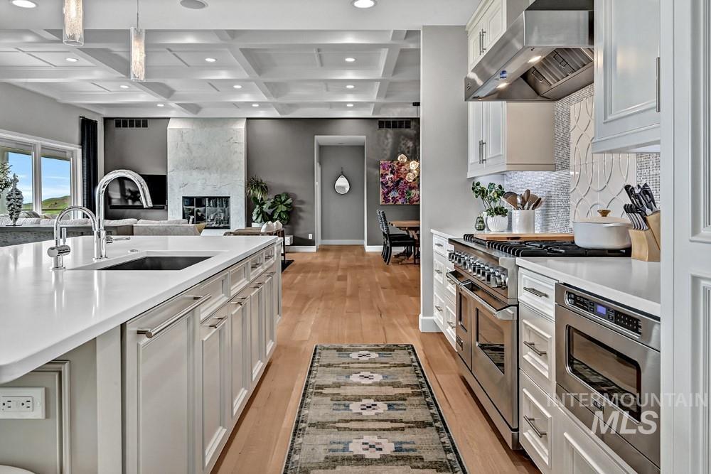 Gourmet kitchen featuring a large island with sink, stainless steel appliances, white cabinetry, and hardwood flooring