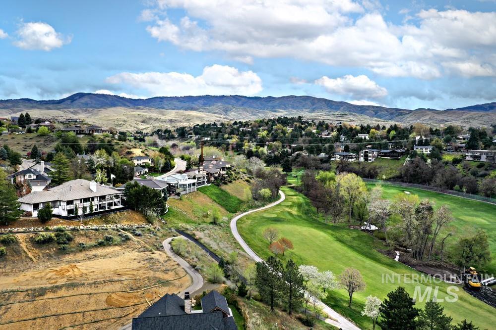 Expansive landscape featuring a golf course, surrounding residential properties, mature trees, and mountainous terrain