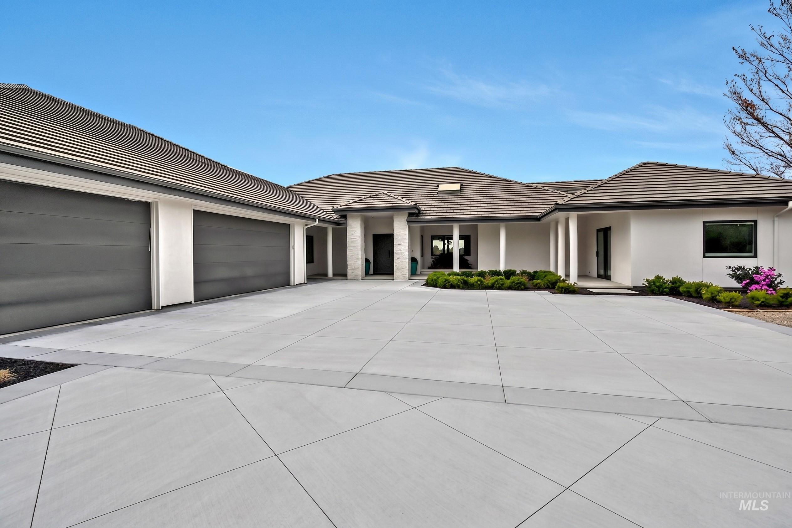 Expansive concrete driveway with geometric scoring, providing ample parking and access to the two-car garage