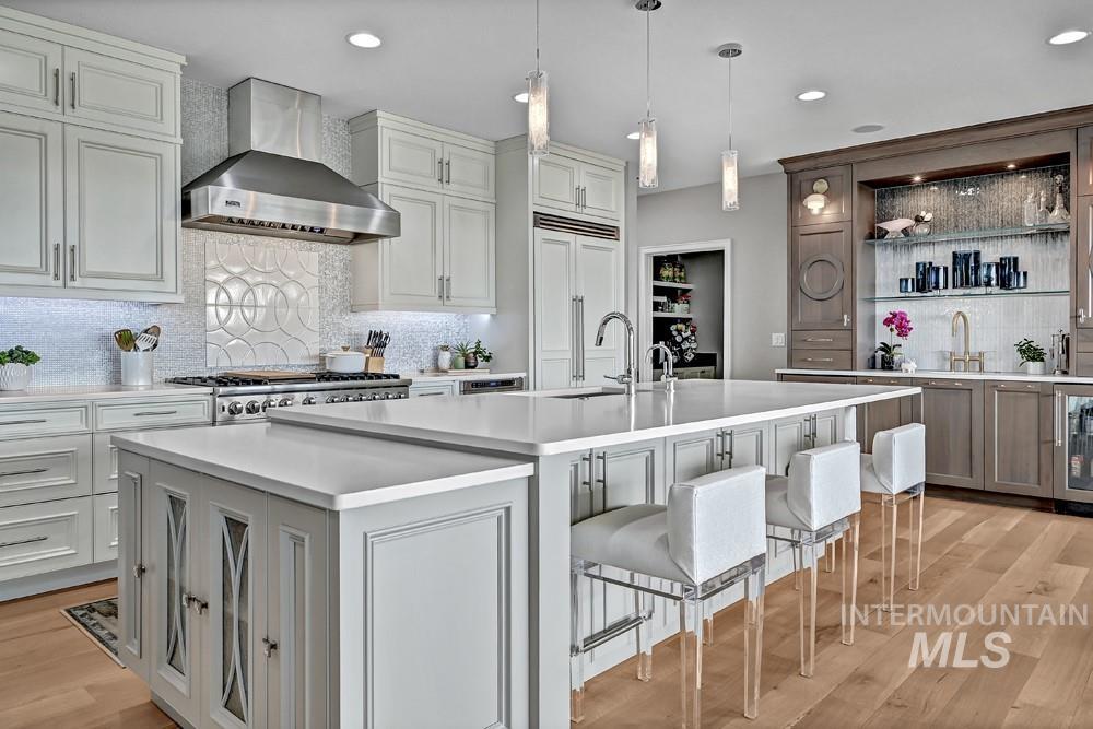 Gourmet kitchen featuring a large central island with seating, stainless steel appliances, and wood-finish flooring
