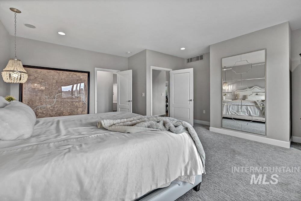 Spacious room featuring light gray walls, recessed lighting, a decorative chandelier, and a full-length mirrored wall accent