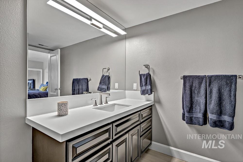 Modern bathroom featuring a vanity with a white countertop, an undermount sink, and a large wall-mounted mirror