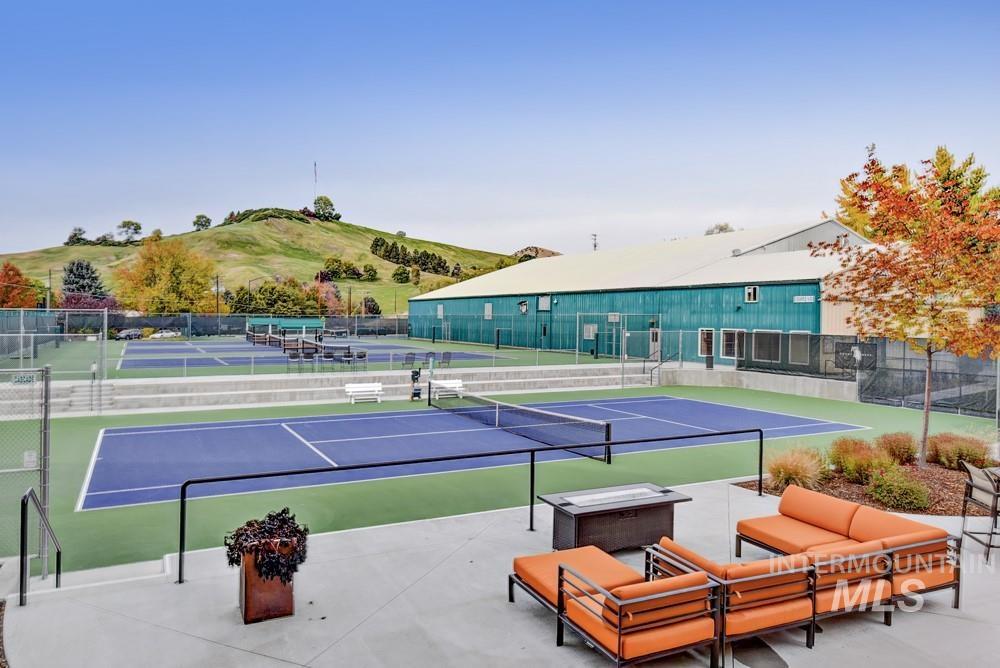 Outdoor hard-surface tennis courts with perimeter fencing and tiered spectator seating