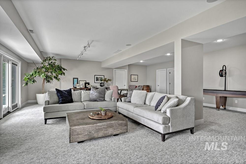 Spacious recreation room featuring light gray carpeting, recessed lighting, track lighting, and a shuffleboard table