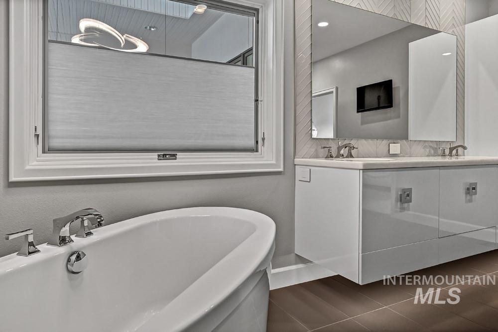 Freestanding soaking tub with chrome fixtures, featuring a top-down/bottom-up cellular shade