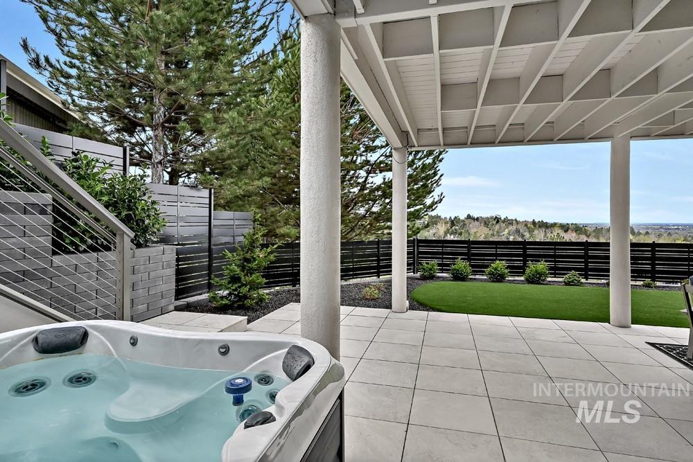 Outdoor spa on a paver patio with a slatted privacy fence