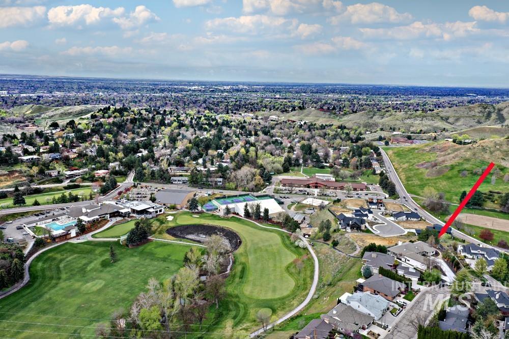 Elevated aerial perspective showcasing a golf course, residential properties, and expansive natural terrain