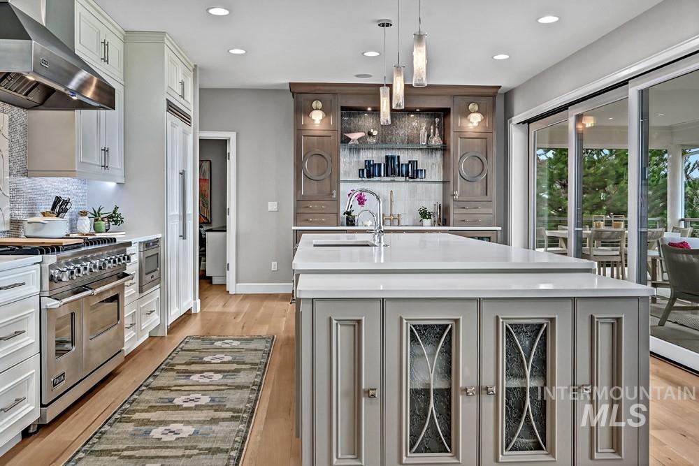 Gourmet kitchen with a large central island, light cabinetry, stainless steel appliances, and wood-finish flooring