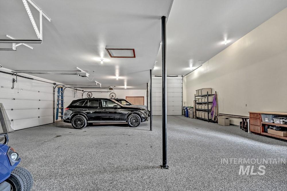 Spacious garage featuring a durable epoxy floor, multiple roll-up doors, and recessed lighting