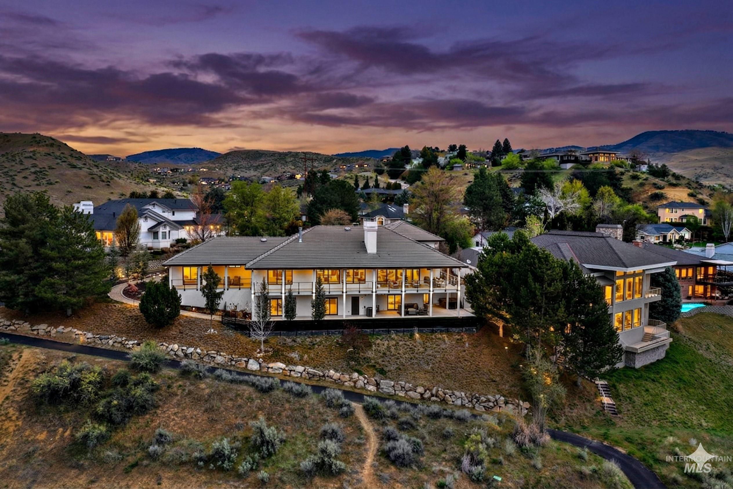 Hillside residence featuring multiple levels of balconies, a dark roof, and extensive exterior lighting