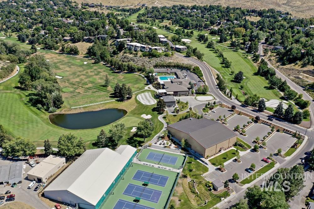 Aerial perspective showcasing extensive golf course fairways, multiple tennis courts, and a large recreational building