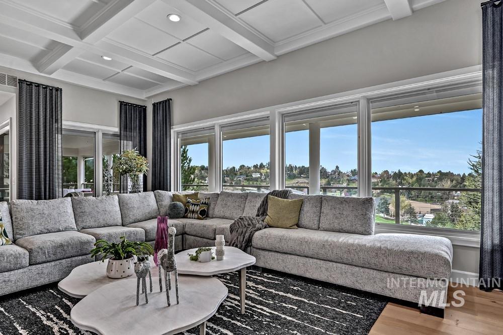 Spacious living area featuring large windows, wood-finish flooring, recessed lighting, and a coffered ceiling