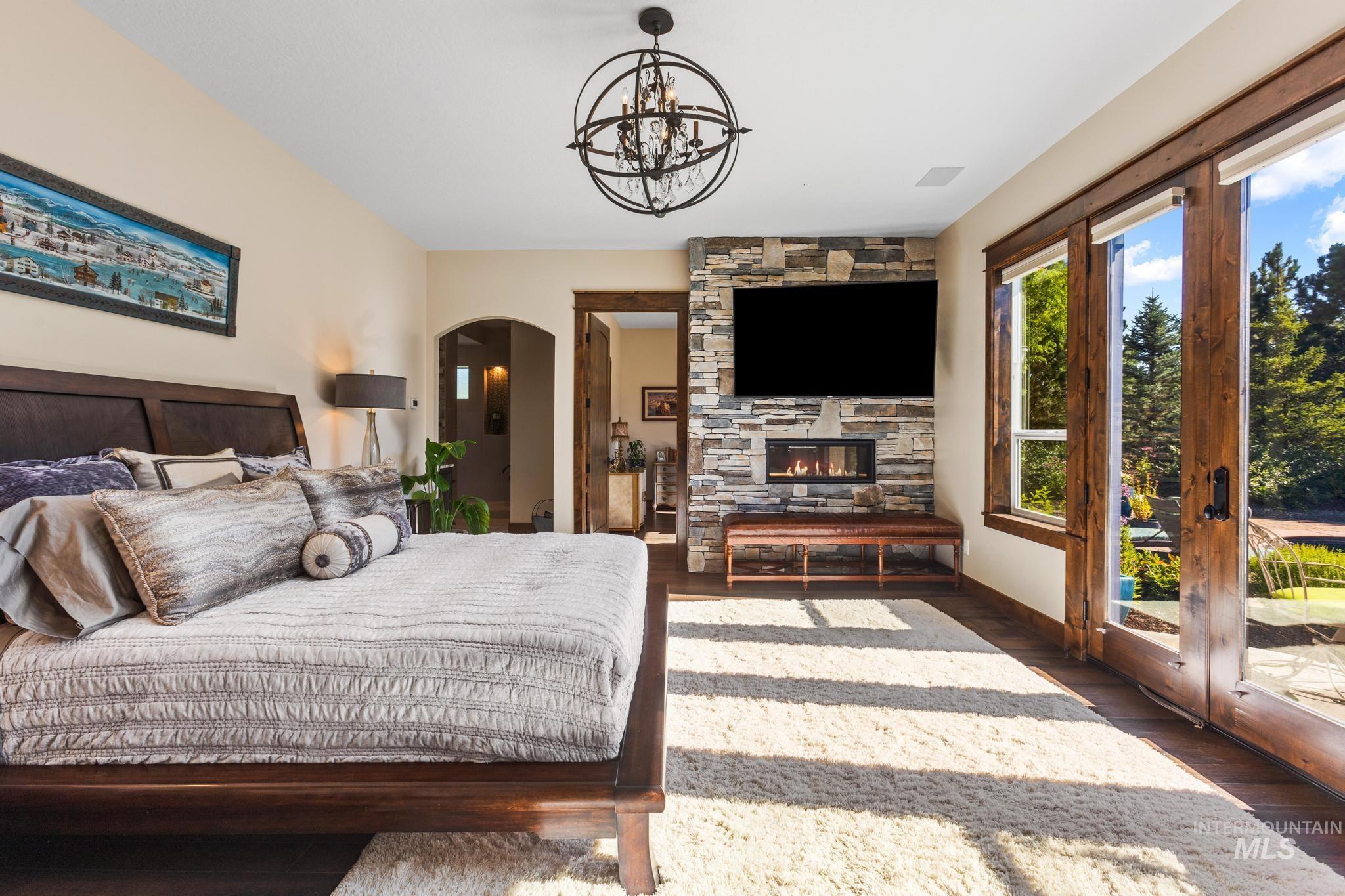 Bedroom featuring arched walkways, a fireplace, wood finished floors, and a chandelier