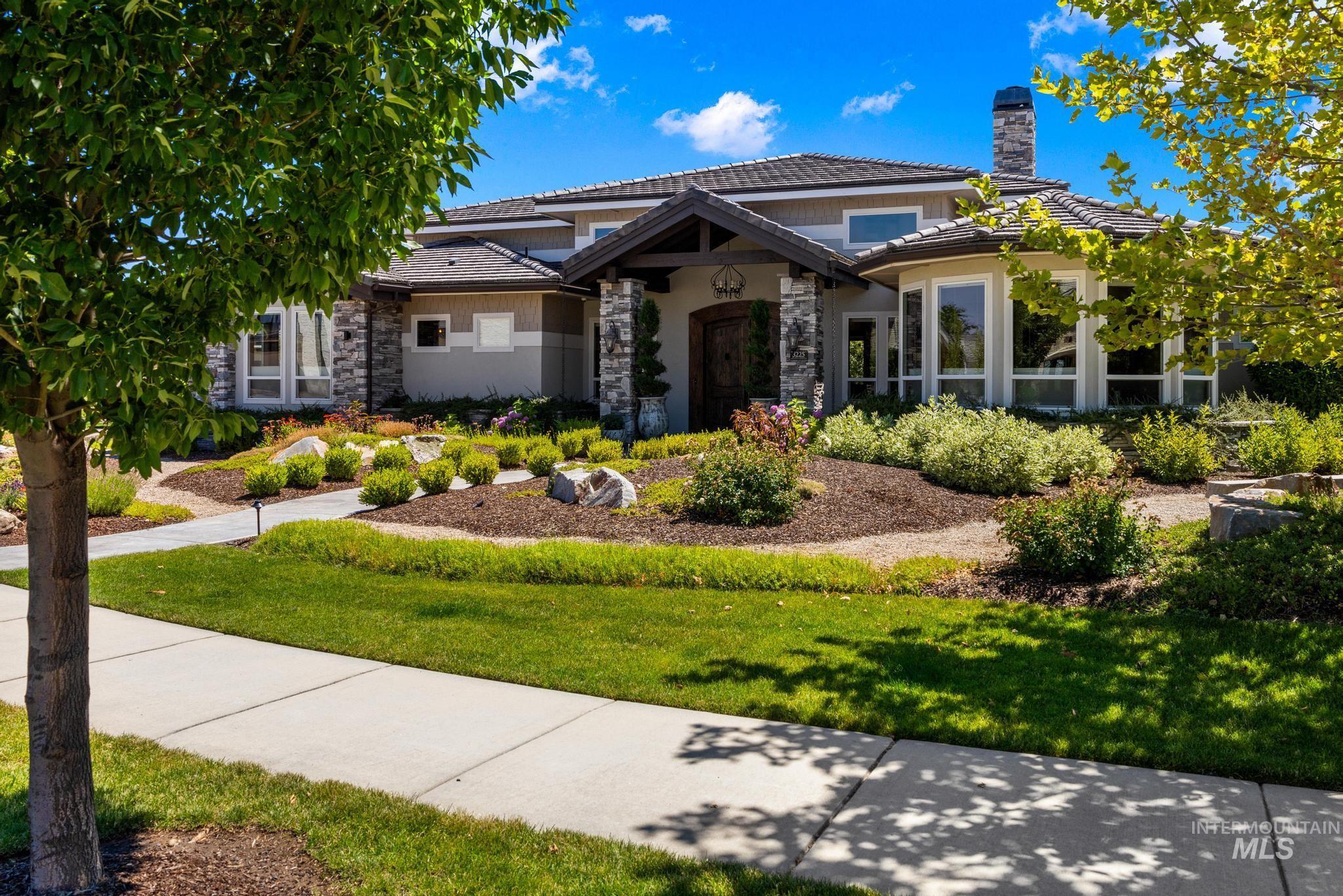View of front of house with a tile roof, stone siding, a front lawn, a chimney, and stucco siding