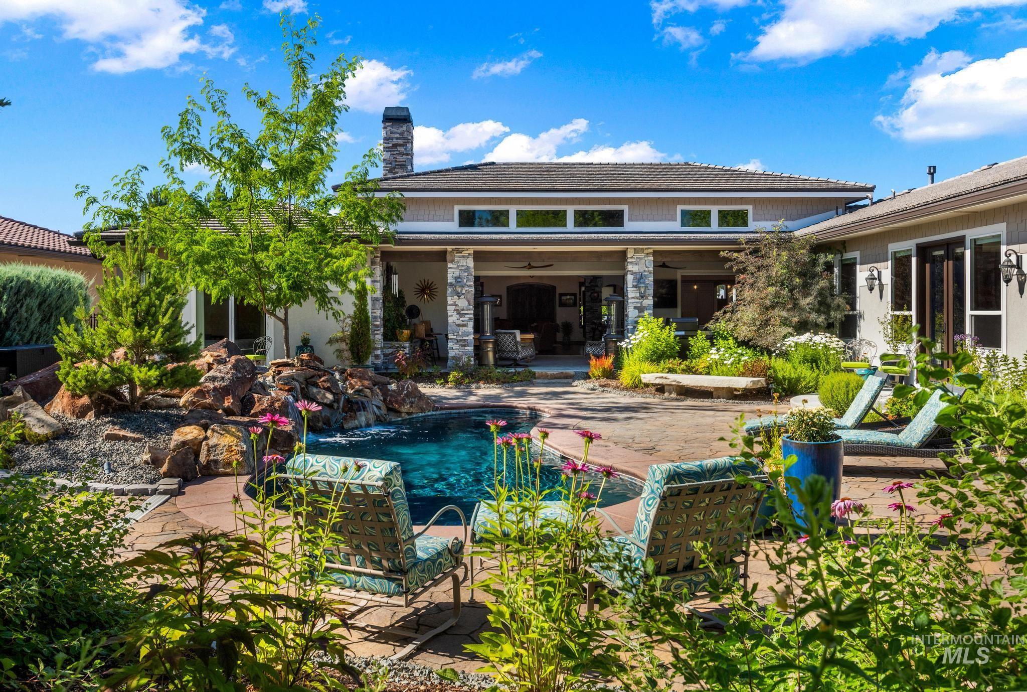 Rear view of house featuring ceiling fan, a patio area, a chimney, an outdoor pool, and stone siding