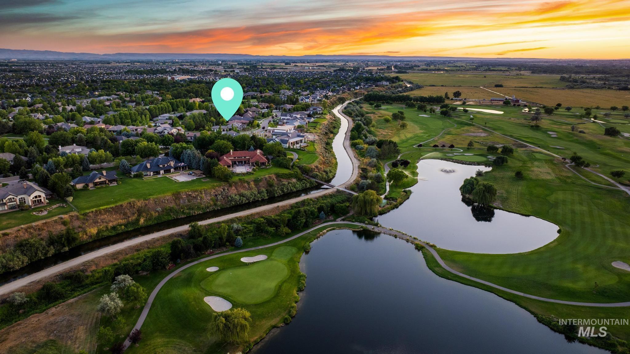 Aerial view at dusk of a water view, view of golf course, and a residential view