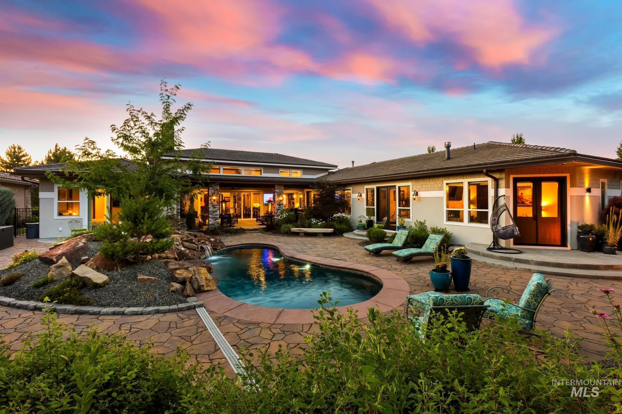 Back of property at dusk featuring a patio area, an outdoor pool, and stucco siding
