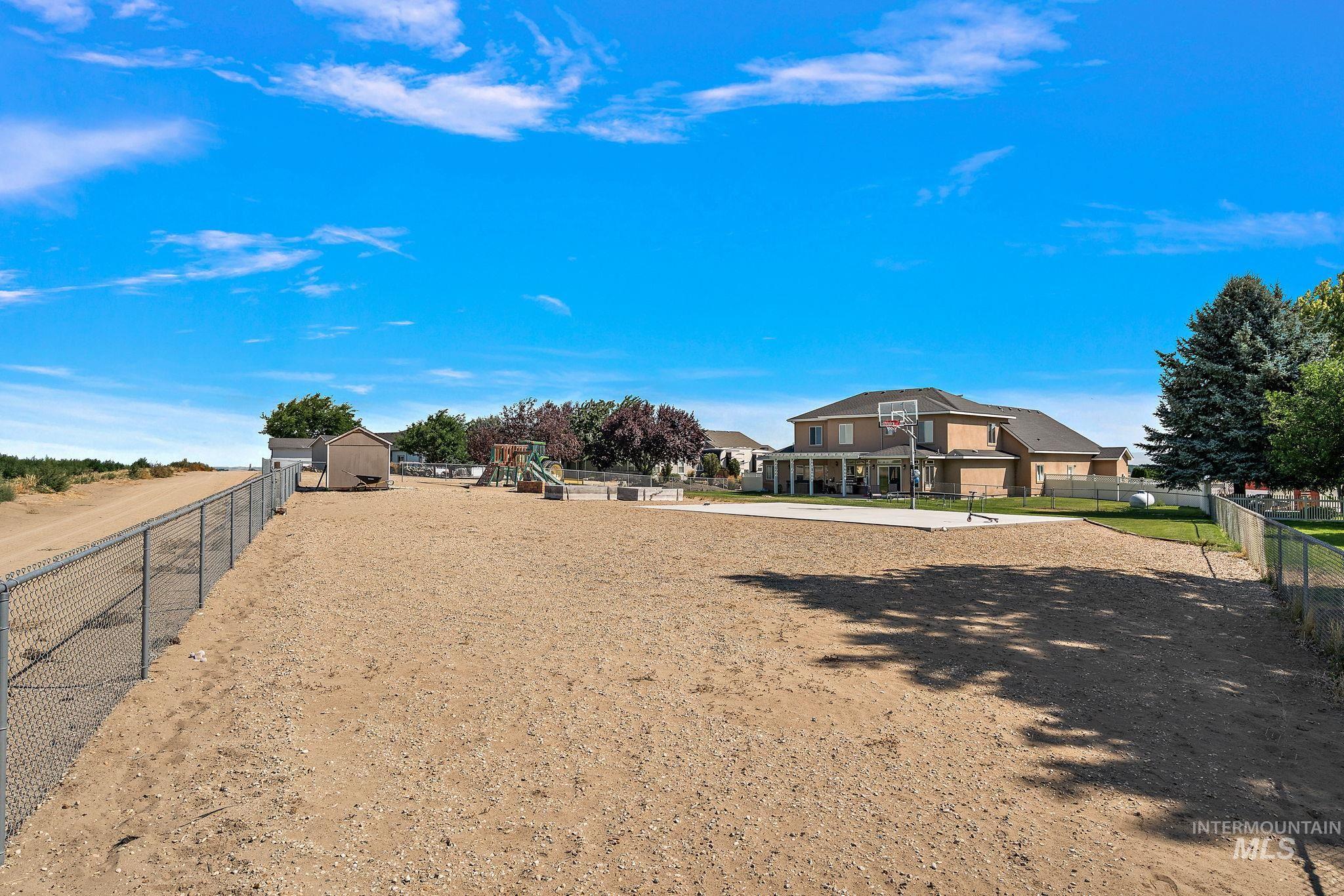 View of yard with a storage shed and basketball pad.