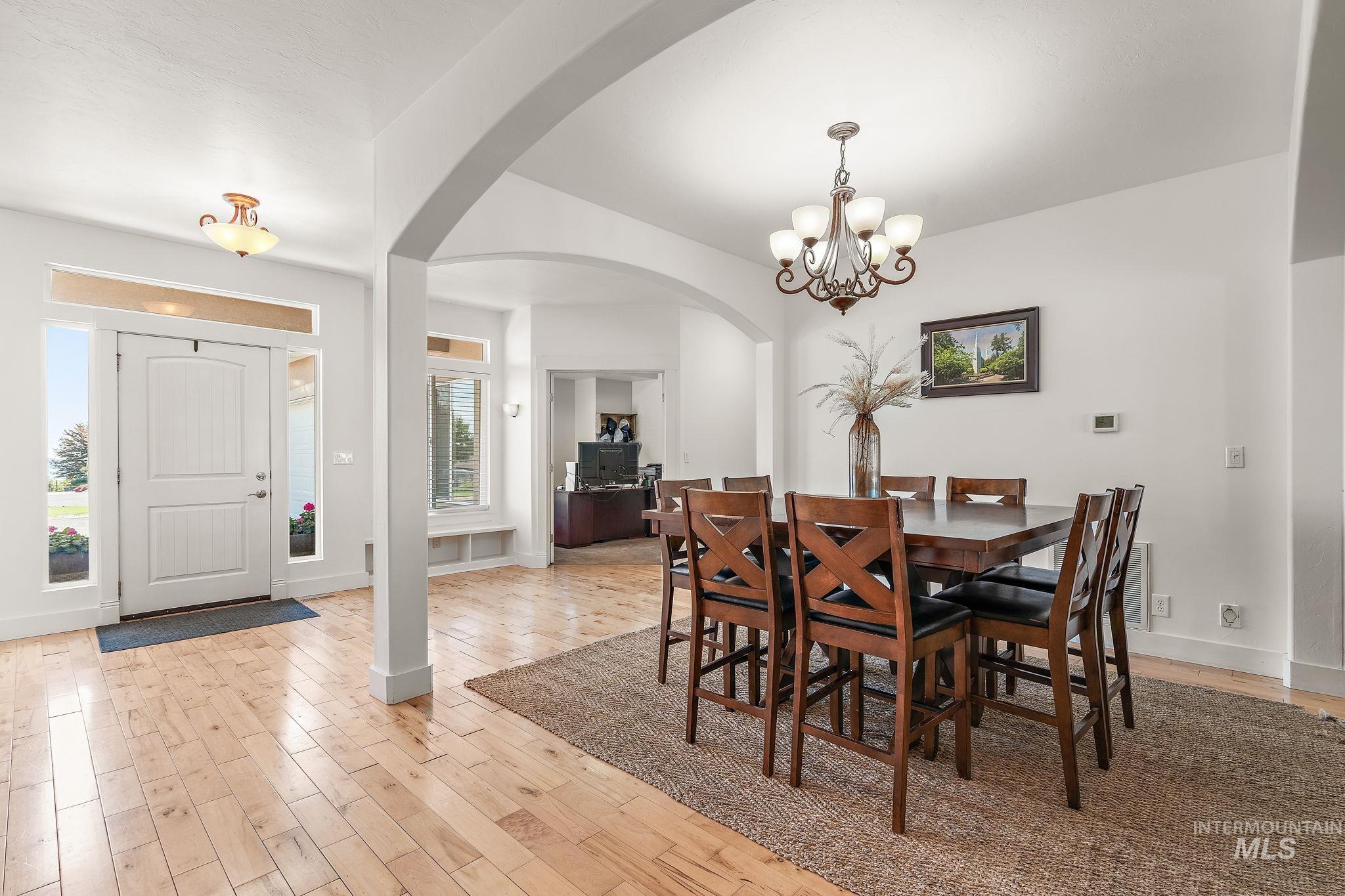 Dining room with light wood-style floors, arched walkways, and a chandelier