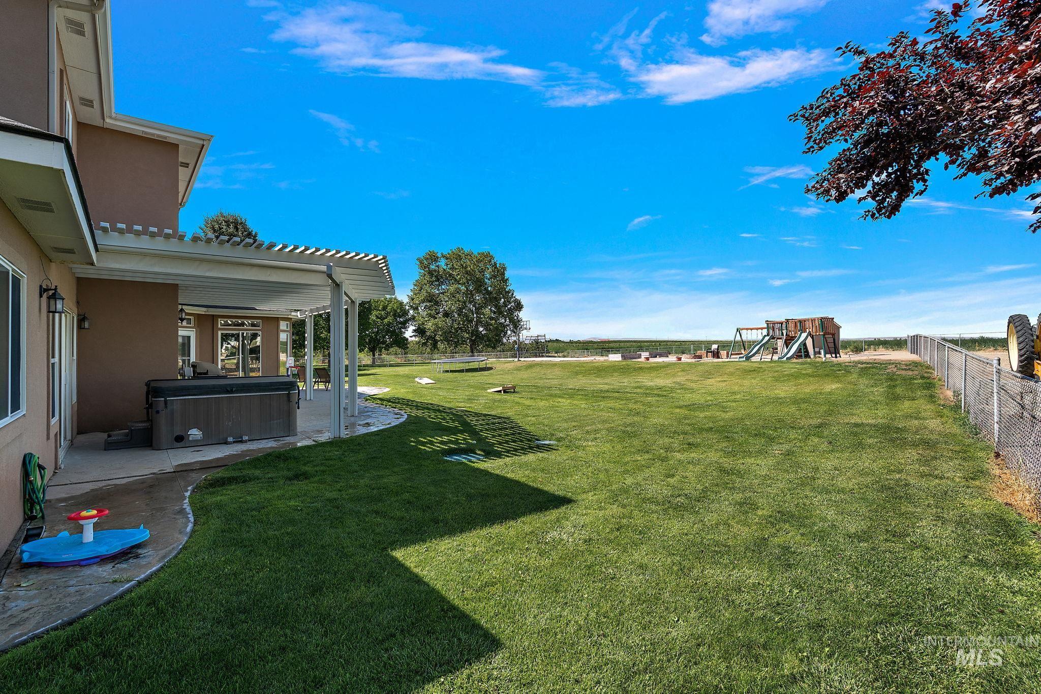 Fenced backyard with a hot tub, a playground, and a patio area